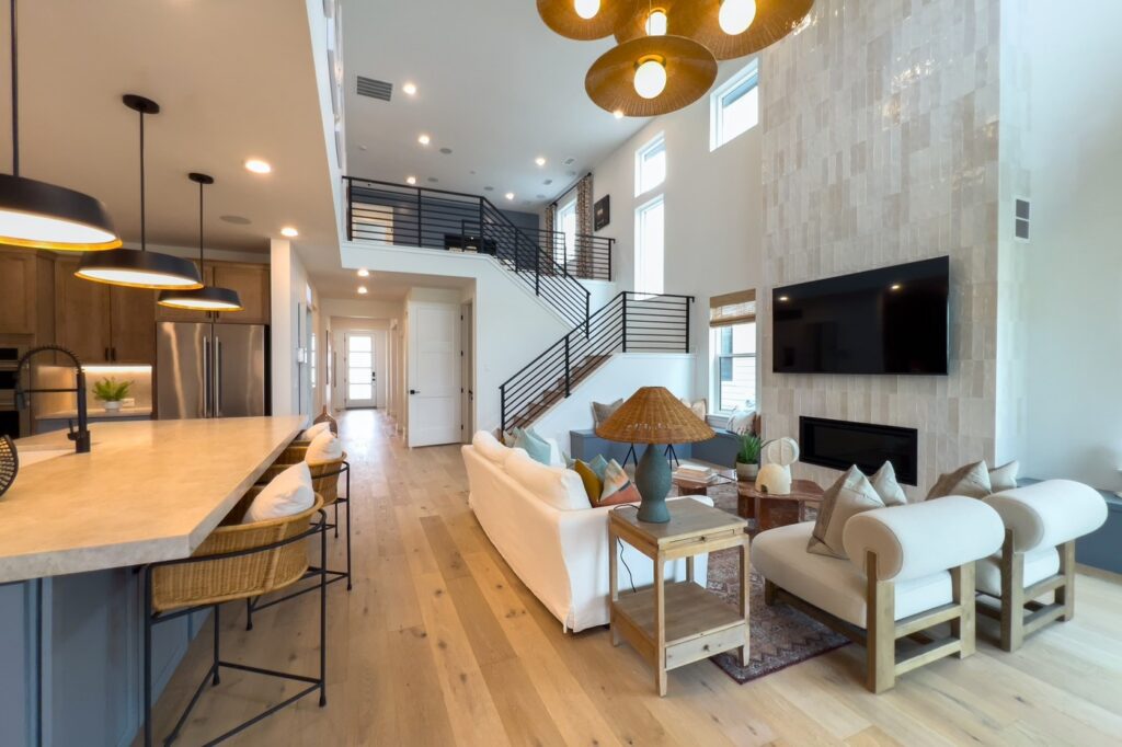 Modern open floor plan featuring a designer kitchen, living room, staircase, and fireplace.