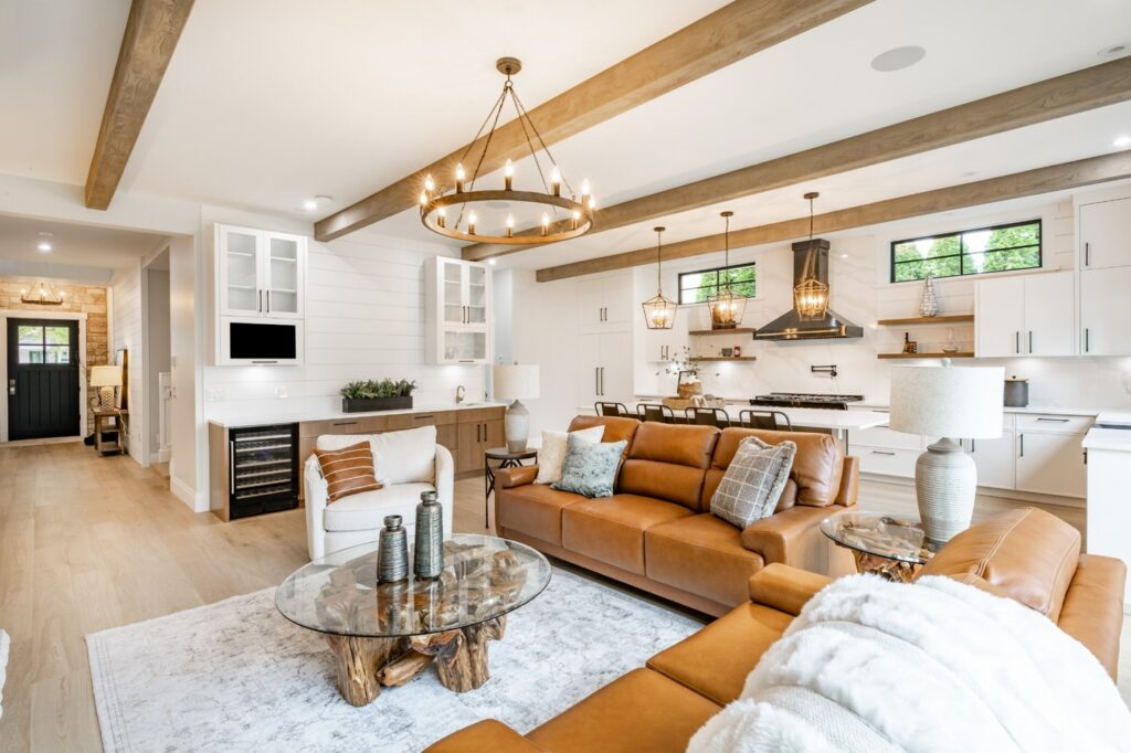 Luxury open concept living room with modern kitchen, exposed wood beams, and designer finishes.