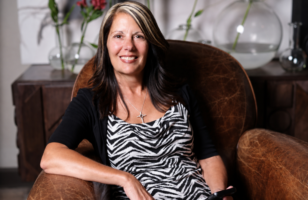 headshot Becky northeast georgia real estate agent Becky Parker smiling while seated in a leather chair, showcasing a warm and approachable presence for real estate and client focused services in Northeast Georgia.