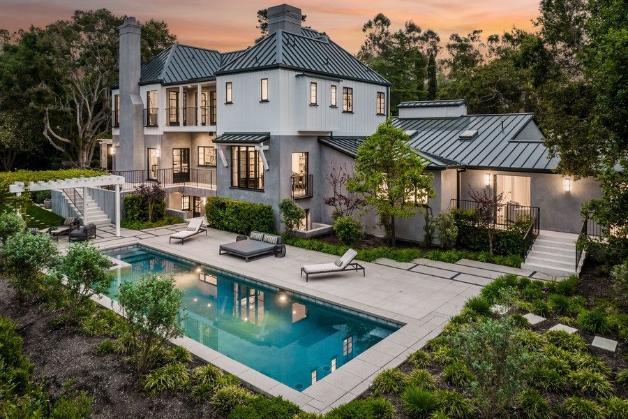 Luxury modern home with resort style swimming pool, landscaped backyard, and elegant outdoor living space at sunset