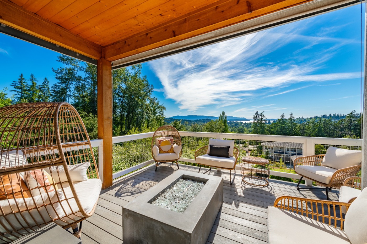 Covered outdoor deck with comfortable seating, panoramic nature views, and a spacious entertaining area overlooking scenic landscapes.