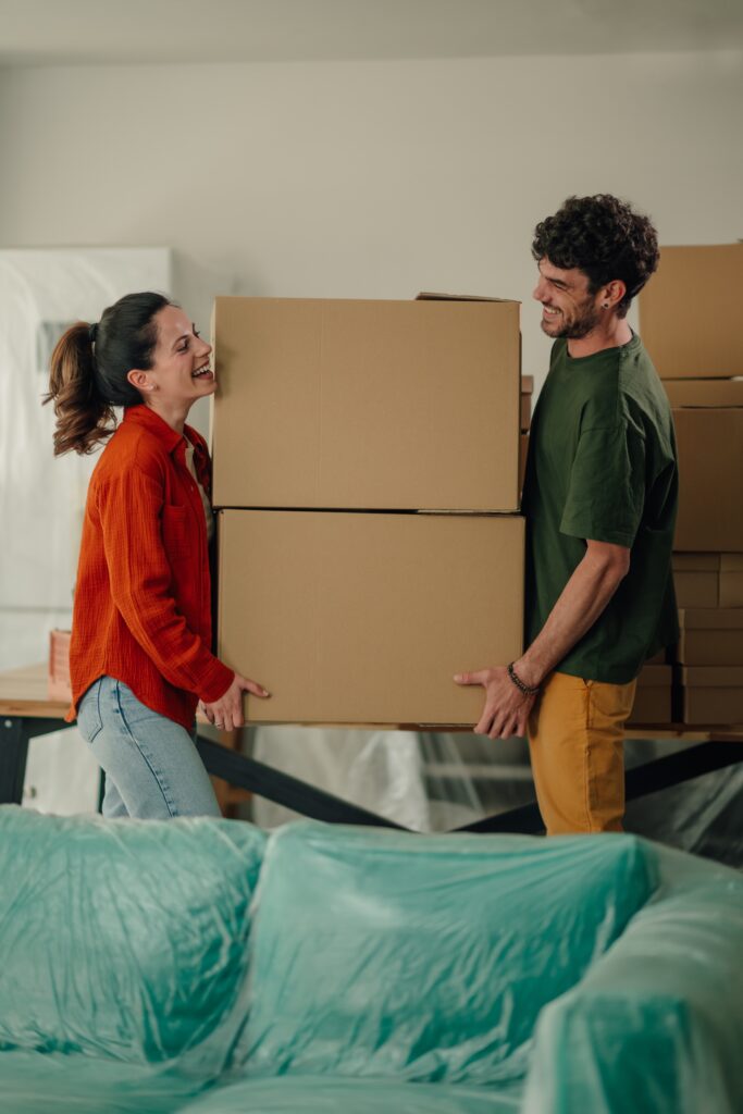 Happy couple carrying moving boxes into their new home during the moving process.