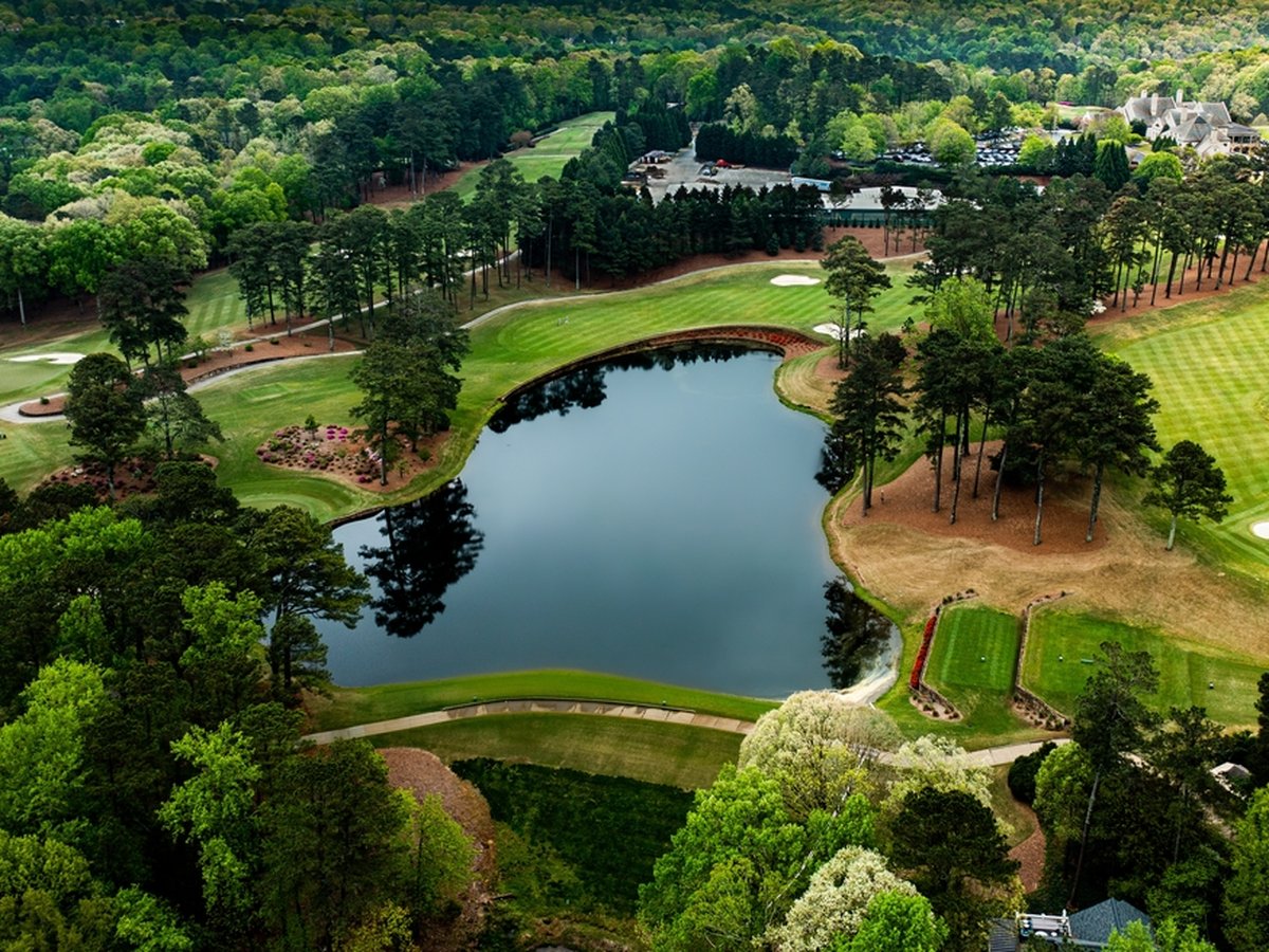  Greensboro golf course community with a scenic lake, manicured fairways, and sand bunkers surrounded by lush trees.